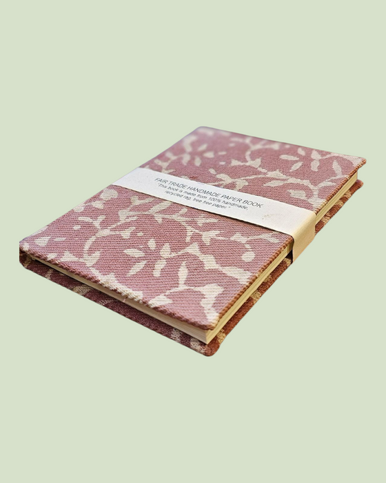Pink notebook with white floral pattern on a light green background