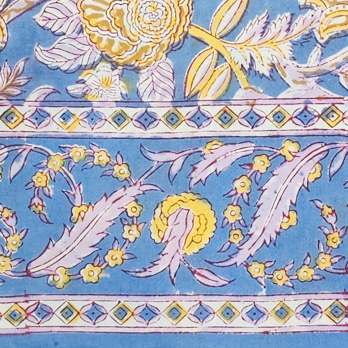Border section of the Aasmani hand-block-printed cotton tablecloth with pink and yellow botanicals on a dusty blue background