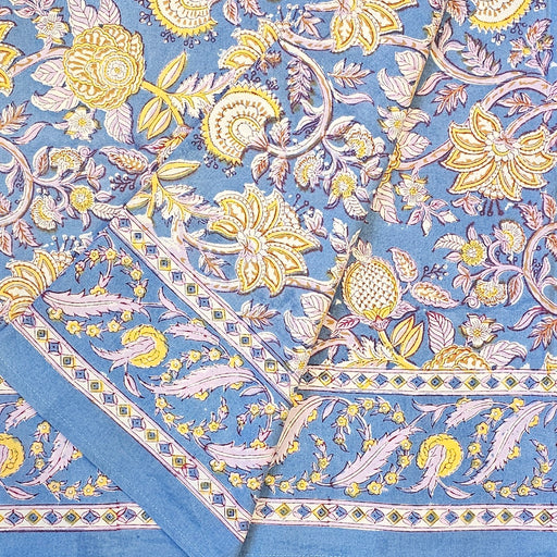 Aasmani hand-block-printed cotton tablecloth with pink and yellow botanicals on a dusty blue background folded over