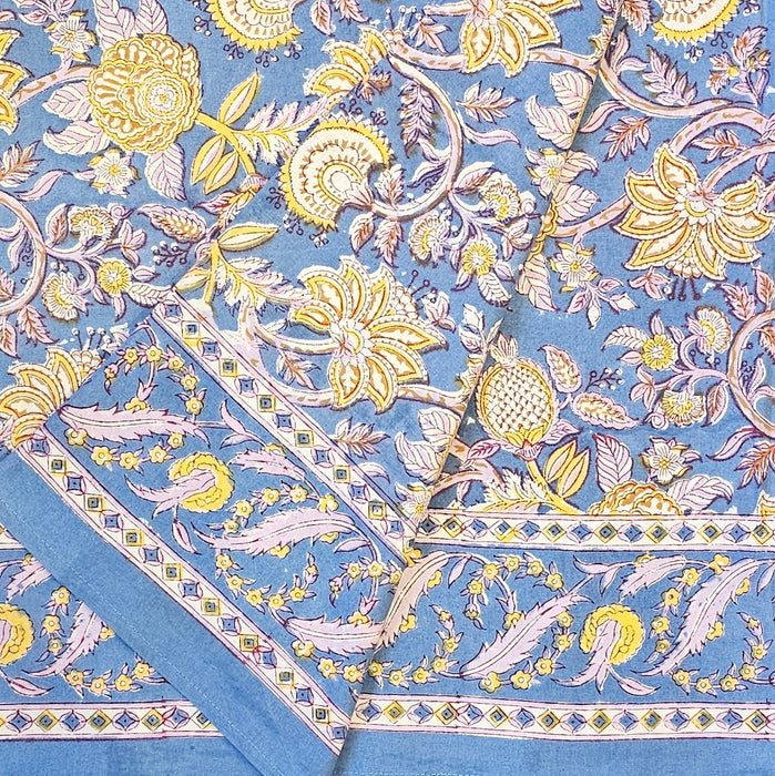 Aasmani hand-block-printed cotton tablecloth with pink and yellow botanicals on a dusty blue background folded over