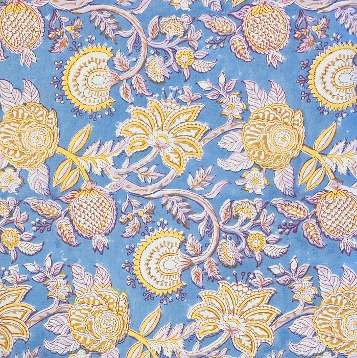 A sectiion of the Aasmani hand-block-printed cotton tablecloth with pink and yellow botanicals on a dusty blue background