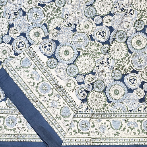 A folded back blue and white tablecloth with a floral block printed design