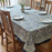 A dining table set with a blue floral tablecloth, plates, and chairs in a room.