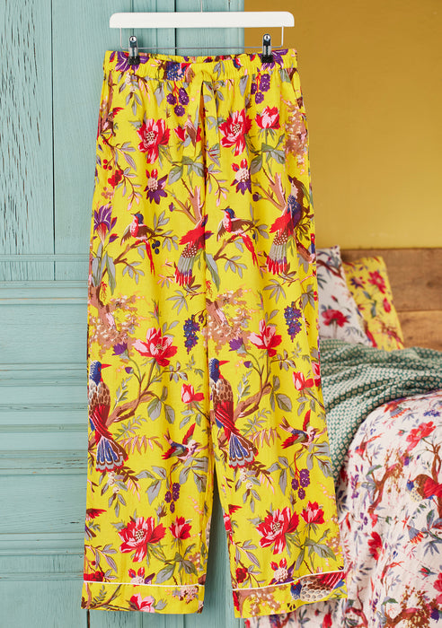 Yellow floral pajama pants hanging on a rack against a colorful background.