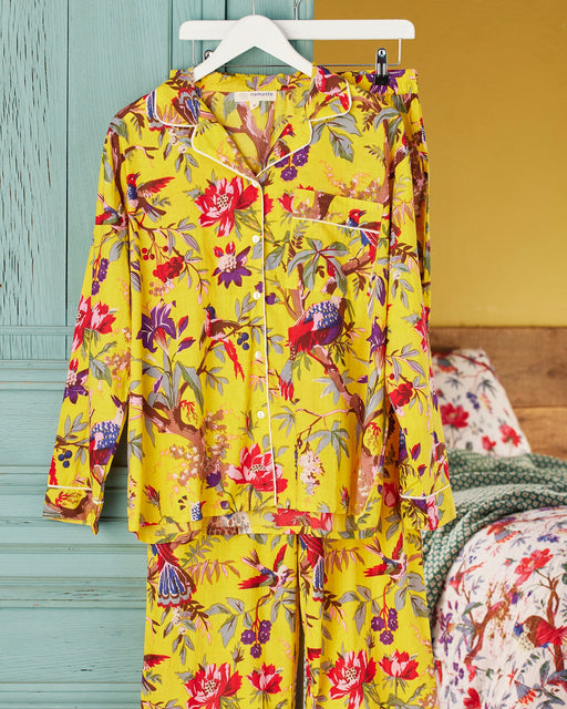 Yellow floral pajama set hanging on a hanger against a colorful background