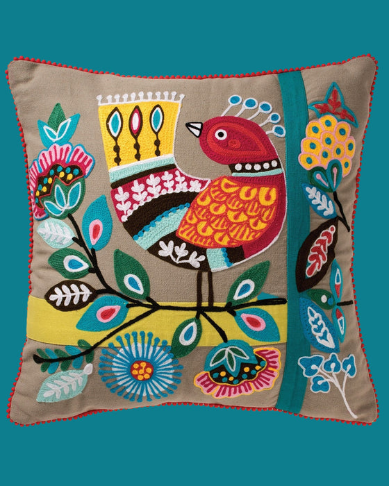 Decorative pillow with colorful bird and floral pattern on a beige background