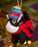 Felt black and white cat ornament with a colorful hat and red scarf hanging on a Christmas tree.