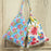 Two floral-patterned bags hanging on a wooden surface.