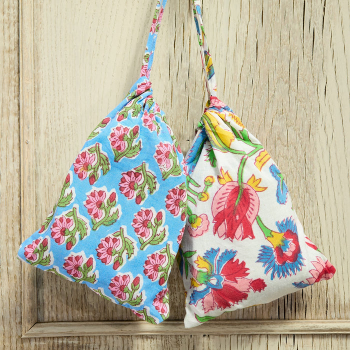 Two floral-patterned bags hanging on a wooden surface.