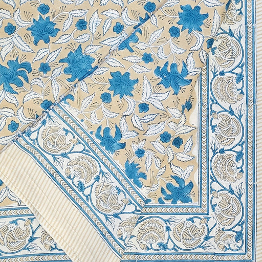 Floral-patterned fabric with blue and white flowers on a beige background, folded at one corner to show the border design