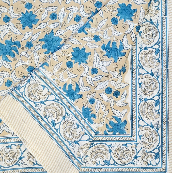 Floral-patterned fabric with blue and white flowers on a beige background, folded at one corner to show the border design