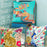 Colorful animal-themed pillows on a chair against a light blue wall.