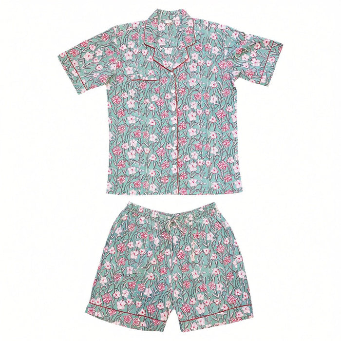 A two-piece short-sleeve pyjama set featuring a matching button-up shirt and shorts in a green floral print with pink and white flowers, accented by thin red piping.