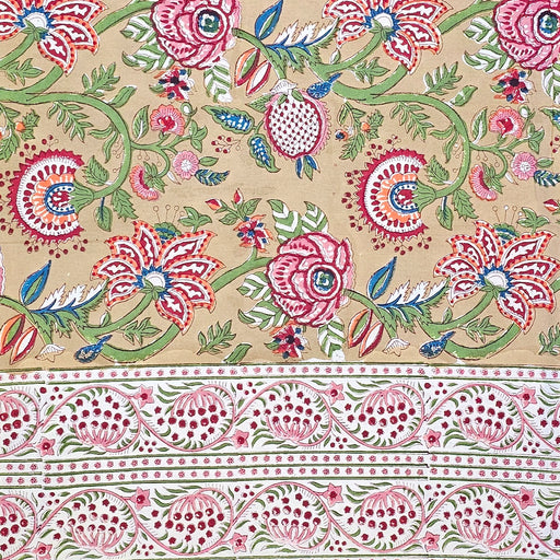 Top-down view of a Crimson Anar Sanganeri hand-block printed cotton tablecloth featuring a wide terracotta red floral border and a warm sand-colored background