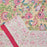 Folded cotton fabric showcasing the Crimson Anar print and the contrast between the intricate floral jaal and the solid crimson clay edge."