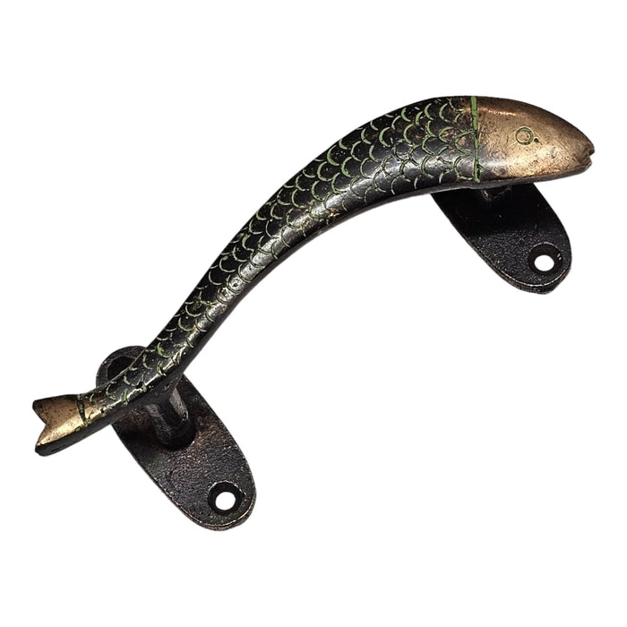 A brass handle in the shape of a green curved fish, with a green patina set against a white background.