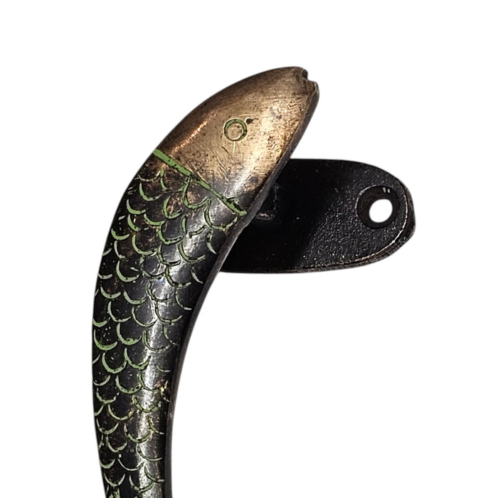 Decorative brass handle with fish scale design on a white background.