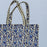 Tote bag with blue and cream floral pattern on a light blue background