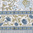 White cotton tablecloth hand-block printed with soft blue flowers and sage green leaves showing the border design.