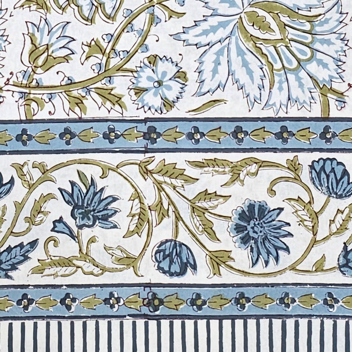 White cotton tablecloth hand-block printed with soft blue flowers and sage green leaves showing the border design.