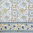 White cotton tablecloth hand-block printed with soft blue flowers and sage green leaves.