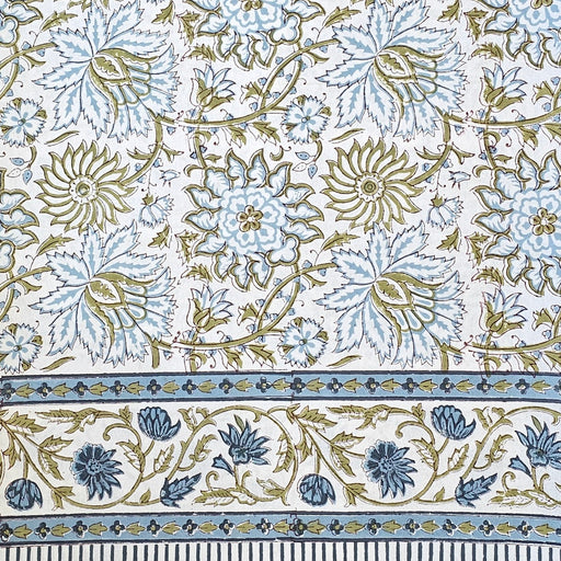 White cotton tablecloth hand-block printed with soft blue flowers and sage green leaves.