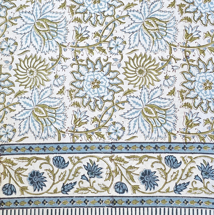White cotton tablecloth hand-block printed with soft blue flowers and sage green leaves.