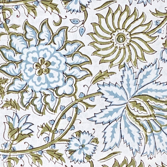 Close up detail of a white cotton tablecloth hand-block printed with soft blue flowers and sage green leaves.
