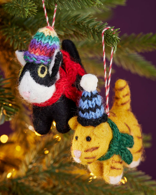 Knitted cat ornaments with colorful hats and scarves hanging on a Christmas tree.