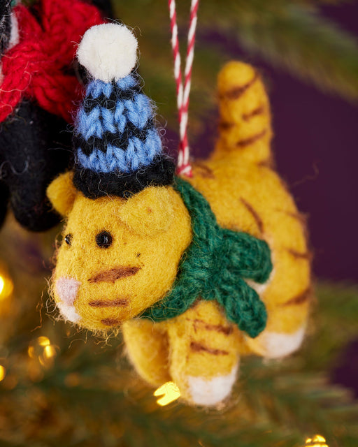 Felt Ginger Cat ornament with a blue and black hat and green scarf on a Christmas tree.