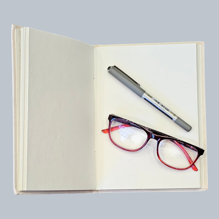 open handmade paper notebook with pen and a pair of glasses on the page 