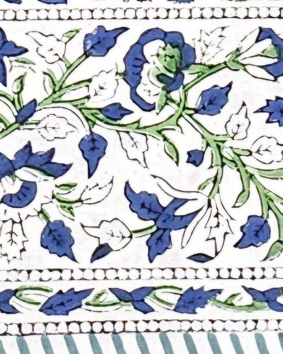 Close up of the border of a tablecloth with a blue and green floral motif on a white backgroundGreen Block Print Tablecloth with a Yellow and Blue Floral Motil