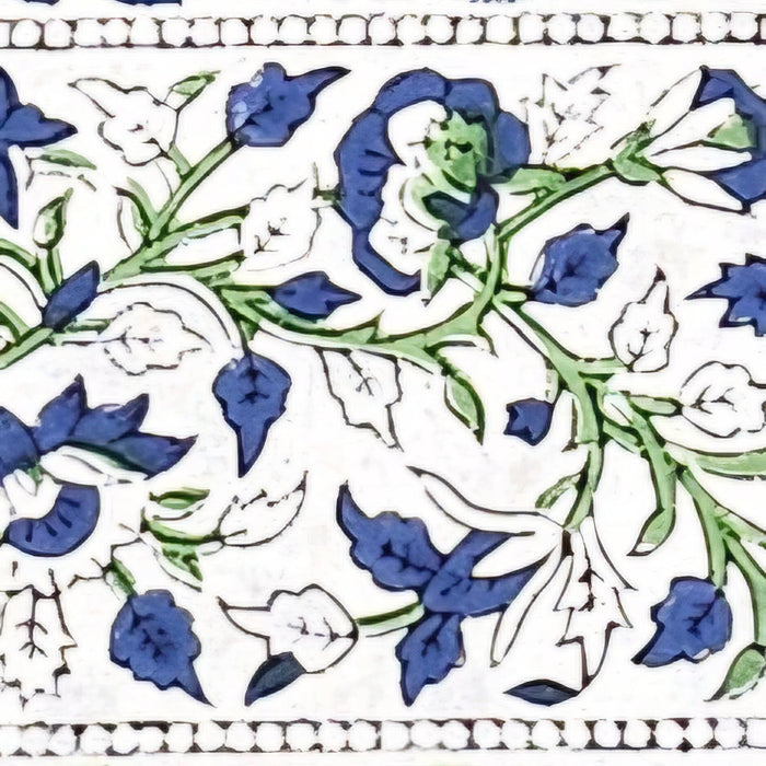 Close up of the border of a tablecloth with a blue and green floral motif on a white backgroundGreen Block Print Tablecloth with a Yellow and Blue Floral Motil