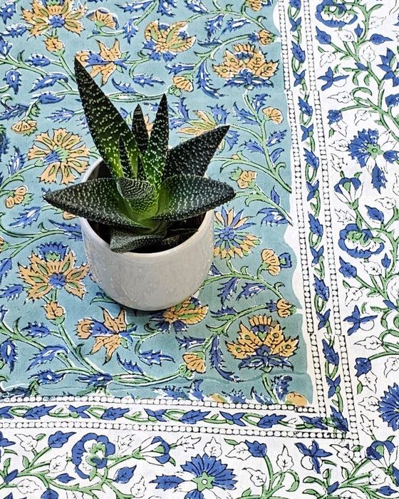  House plant in a white pot placed on the corner of a green tablecloth with a floral motif