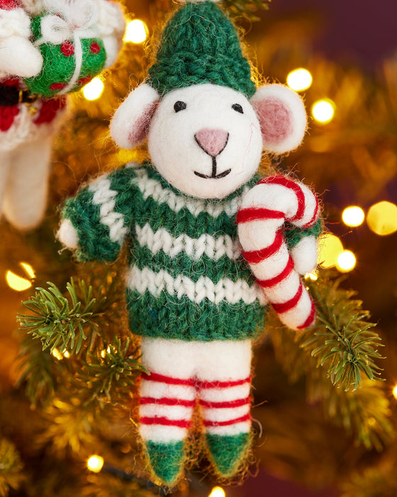 Decorative mouse ornament in a green sweater and striped pants, holding a candy cane, on a Christmas tree.