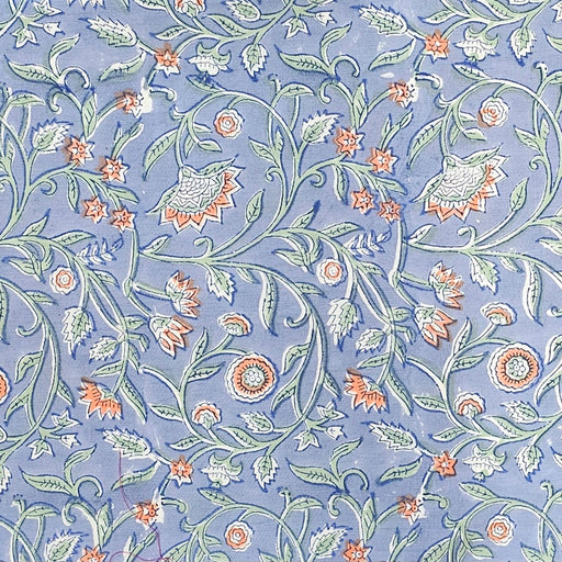 Close up picture of a blue block printed cotton tablecloth with a green and orange floral design.