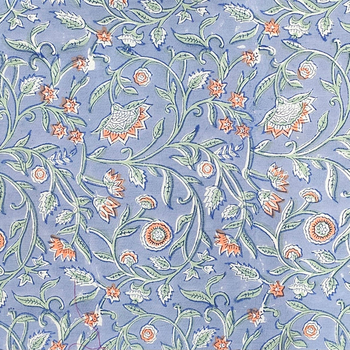 Close up picture of a blue block printed cotton tablecloth with a green and orange floral design.