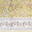 Block print tablecloth with yellow background and floral patterns in pink and green with a floral border.