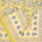 A hand block printed tablecloth with a blue and grey foral design on a mustard yellow background, folded back at one corner.
