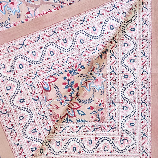 Close-up of a patterned fabric with intricate designs on a pinky beige background
