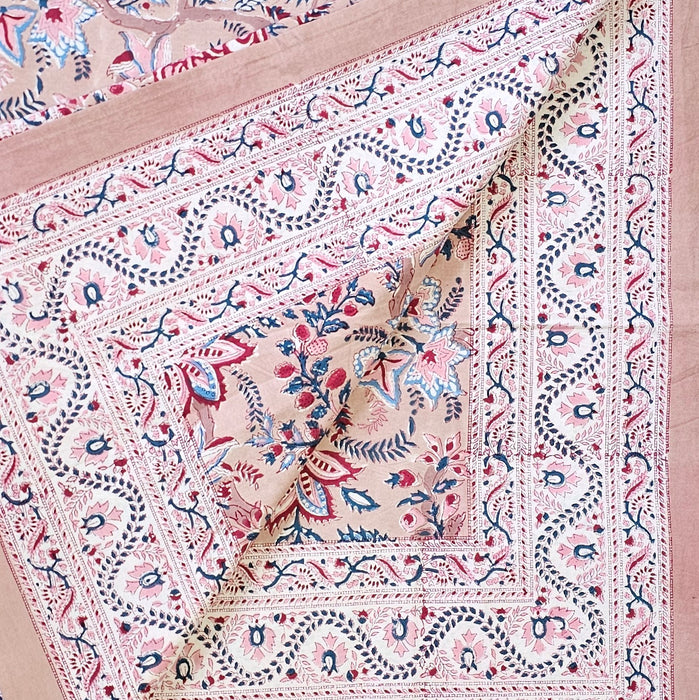 Close-up of a patterned fabric with intricate designs on a pinky beige background