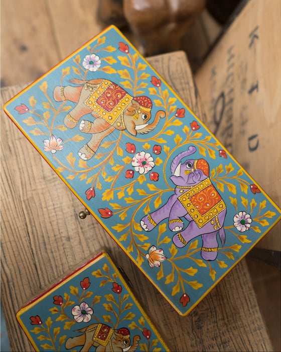 Decorative boxes with elephant designs on a wooden surface