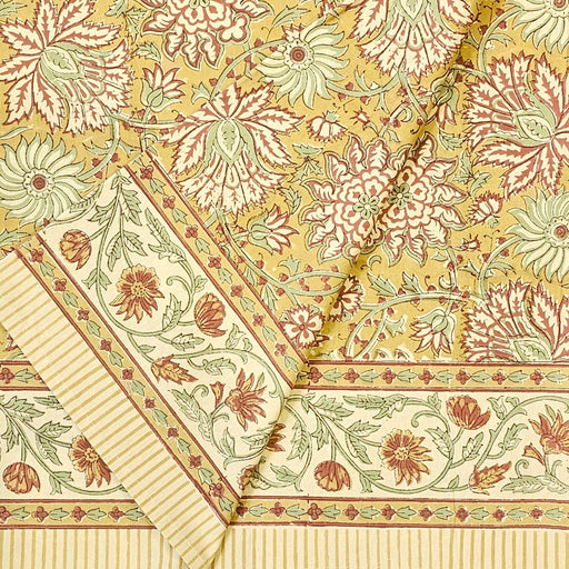 Golden turmeric hand-block printed cotton tablecloth with terracotta floral vines and sage green accents shown folded.