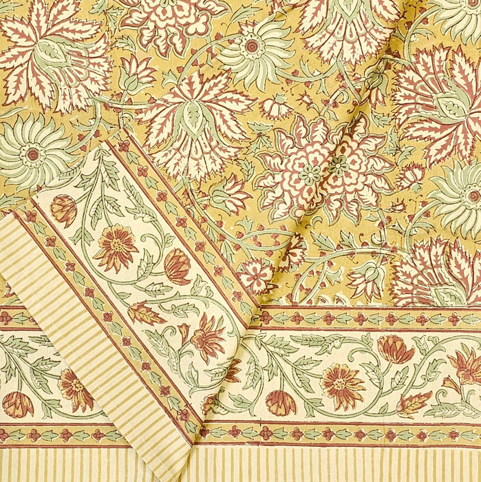 Golden turmeric hand-block printed cotton tablecloth with terracotta floral vines and sage green accents shown folded.