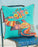 Colourful embroidered pillow with an elephant design on a blue chair against a light blue background