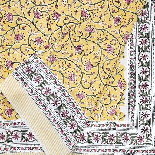 Folded Marigold Jaal design tablecloth with an intricate floral pattern on a yellow background