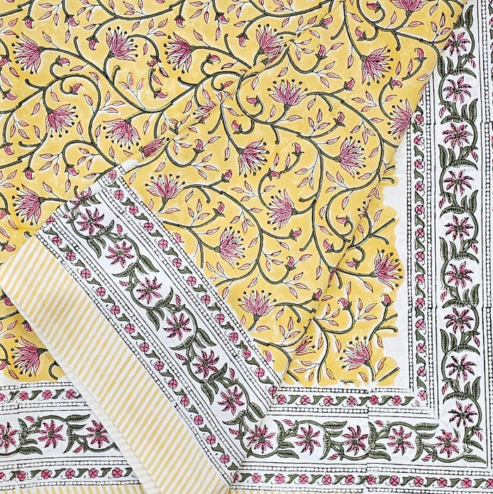 Folded Marigold Jaal design tablecloth with an intricate floral pattern on a yellow background