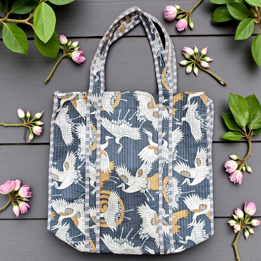 Midnight crane quilted cotton tote bag displayed on a wooden surface with flowers and leaves.