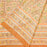 A close-up of a peach-colored fabric tablecloth with an all-over floral block print in green, yellow, and brown, featuring a wide decorative border.  The fabric is folded.