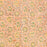 A close-up of a peach-colored fabric tablecloth with an all-over floral block print in green, yellow, and brown